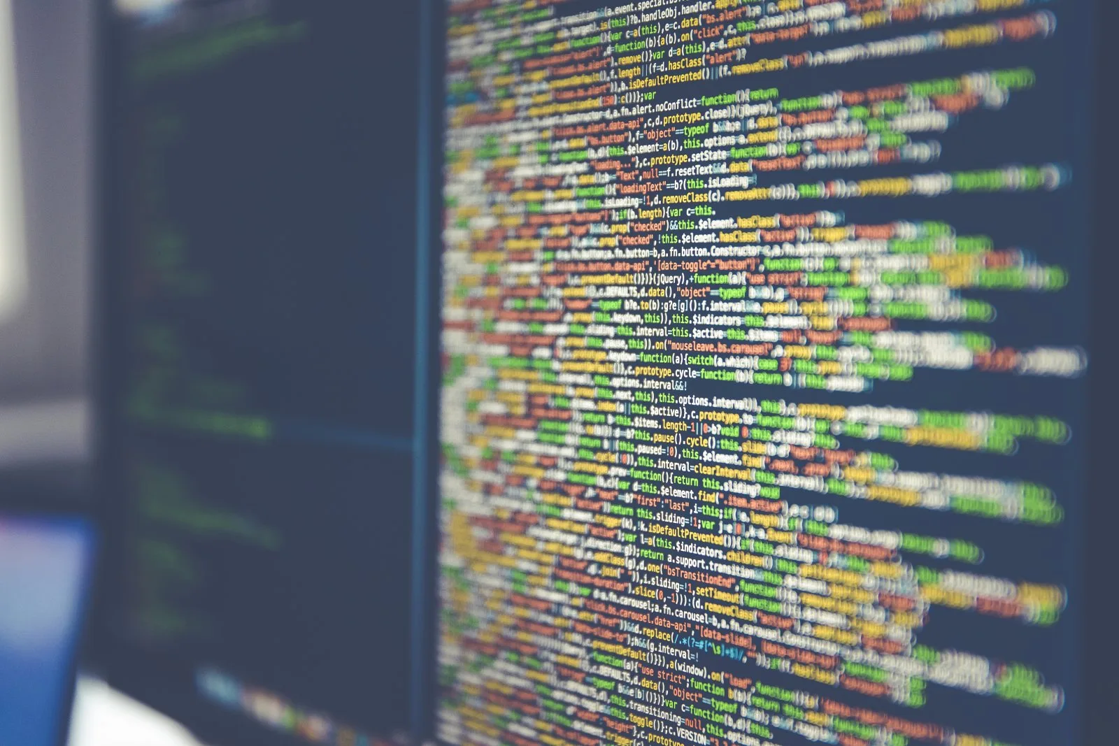 Líneas de código de colores en un monitor, desenfocadas en primer plano