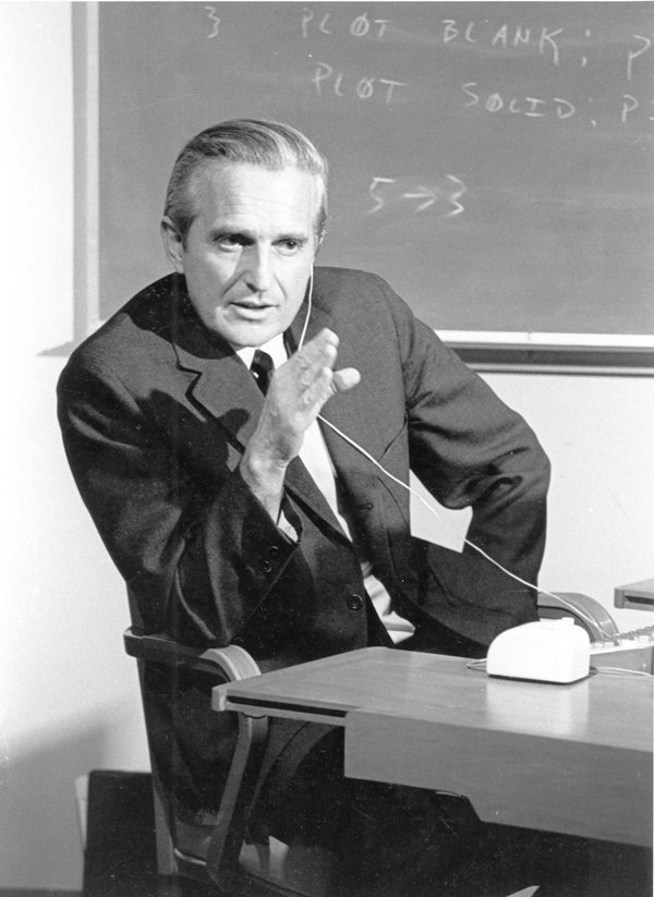 Douglas Engelbart ensayando en 1968, con auriculares y micrófono ante una consola